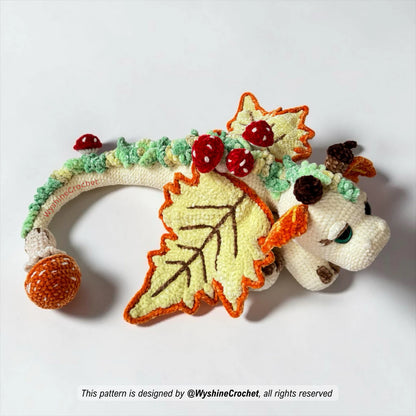 Dragon amigurumi pattern with fall leaves, acorns, mushrooms, grassy spikes, and soft huggable plush texture