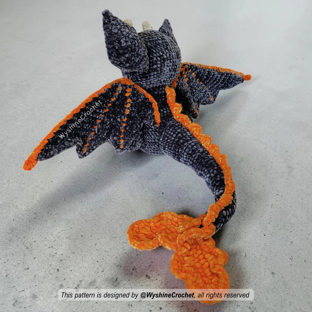 Close-up of Bat Dragon amigurumi face with large safety eyes, pink cheeks, grey chenille yarn, and orange Halloween accents
