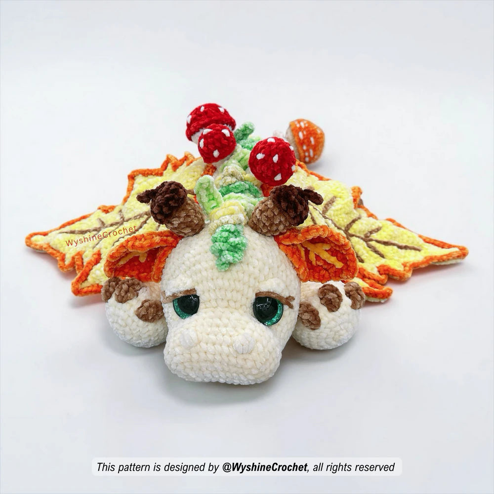 Large dragon crochet pattern with maple leaf wings, grassy back spikes, mushrooms, and cozy fall decor details

