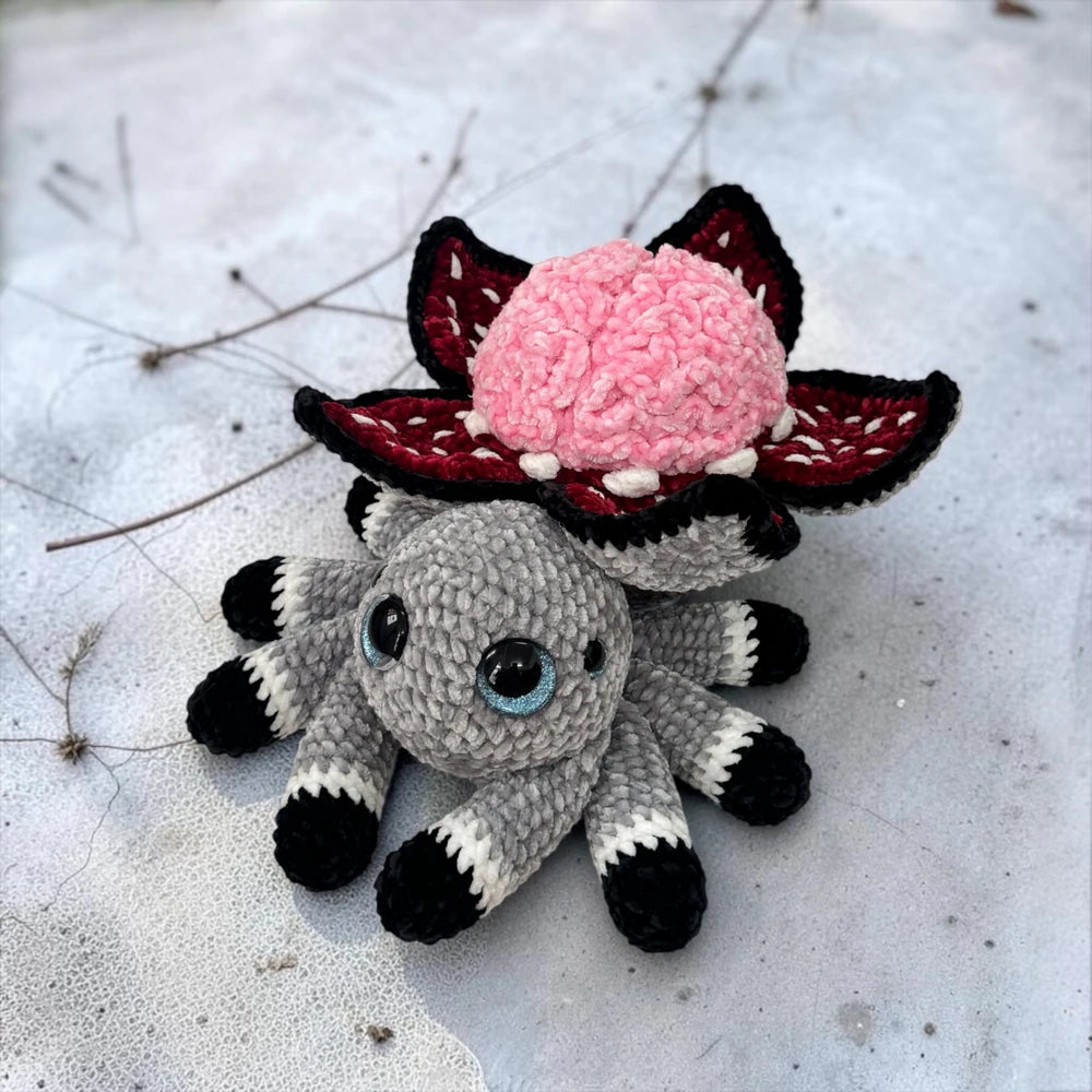  Brain Flower Spider Crochet Pattern finished Halloween amigurumi plushie with pink brain flower, dark red petals, gray spider body, and eight legs
