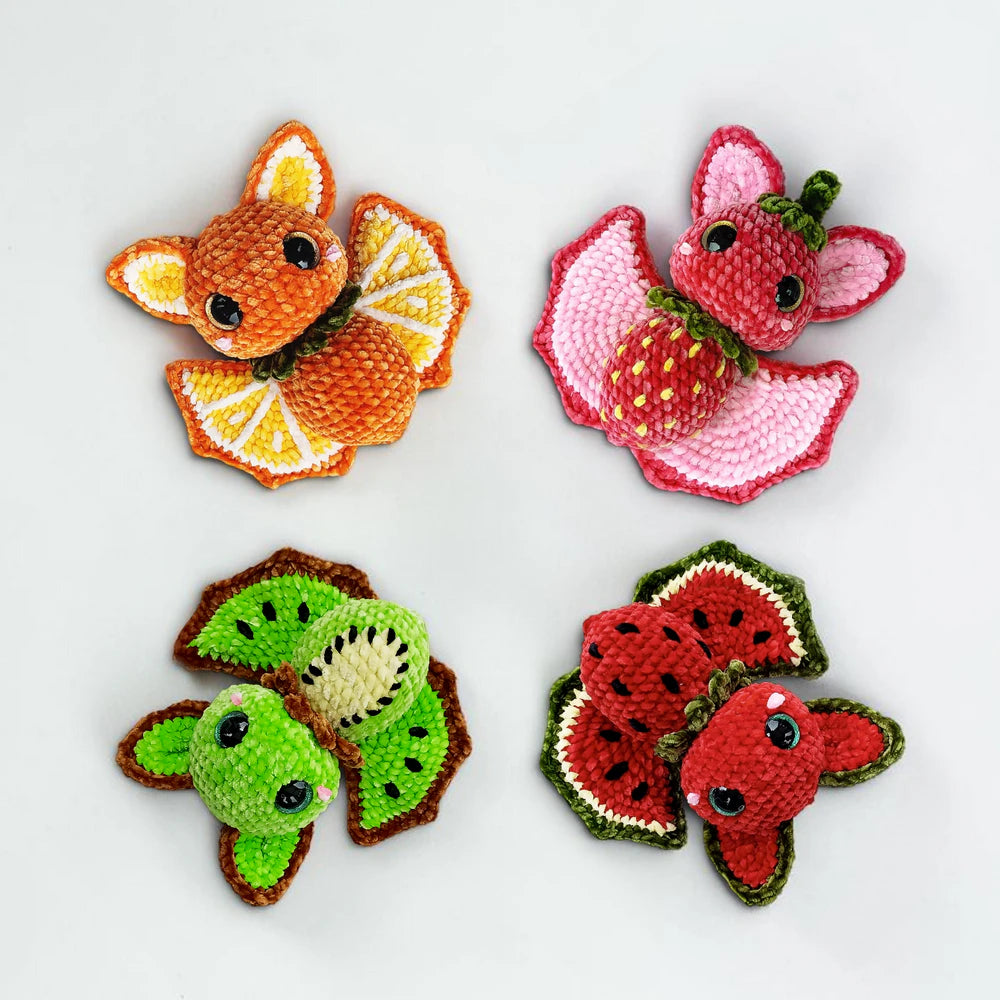 Four fruit bat amigurumi plushies with colorful fruit-inspired wings for spooky-cute Halloween crochet decor