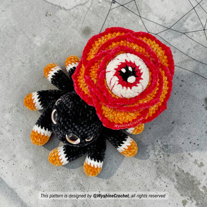 Rose-Eyed Spider amigurumi plushie with layered red and orange crochet petals, black chenille spider body, and creepy cute Halloween look
