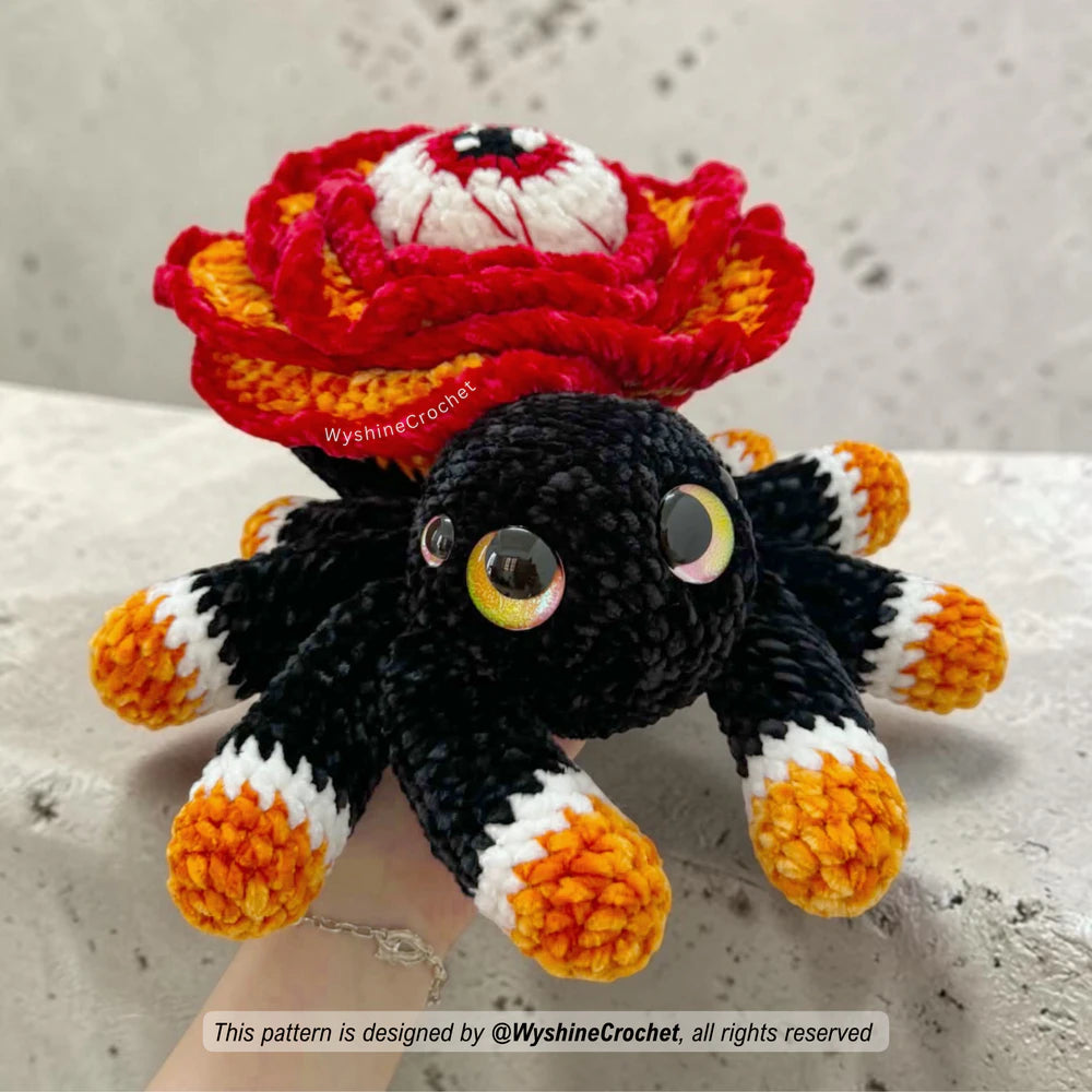 Halloween spider crochet pattern with rose flower body, spooky eye detail, black legs, orange and white foot accents, and fall decor style
